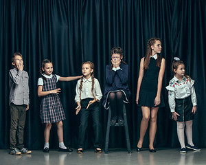 Image showing Cute stylish children on dark studio background. The beautiful teen girls and boy standing together