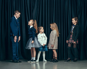 Image showing Cute stylish children on dark studio background. The beautiful teen girls and boy standing together