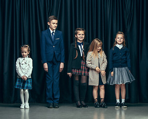 Image showing Cute stylish children on dark studio background. The beautiful teen girls and boy standing together