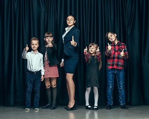 Image showing Cute stylish children on dark studio background. The beautiful teen girls and boy standing together