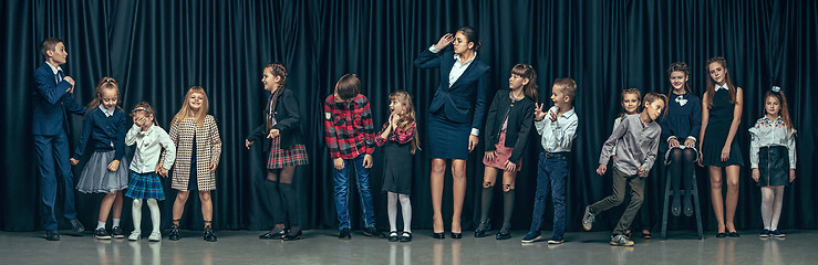 Image showing Cute stylish children on dark studio background. The beautiful teen girls and boy standing together