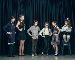 Image showing Cute stylish children on dark studio background. The beautiful teen girls and boy standing together