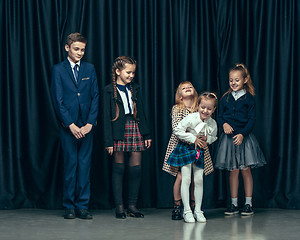 Image showing Cute stylish children on dark studio background. The beautiful teen girls and boy standing together