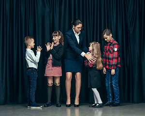 Image showing Cute stylish children on dark studio background. The beautiful teen girls and boy standing together