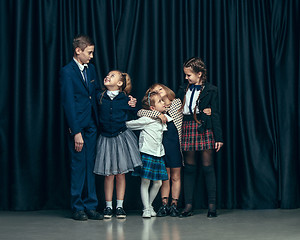 Image showing Cute stylish children on dark studio background. The beautiful teen girls and boy standing together