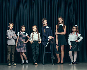 Image showing Cute stylish children on dark studio background. The beautiful teen girls and boy standing together