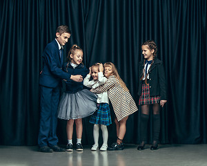 Image showing Cute stylish children on dark studio background. The beautiful teen girls and boy standing together