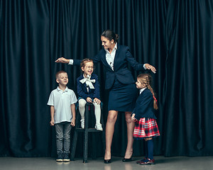 Image showing Cute stylish children on dark studio background. The beautiful teen girls and boy standing together