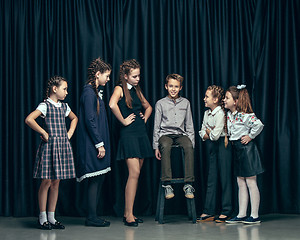 Image showing Cute stylish children on dark studio background. The beautiful teen girls and boy standing together