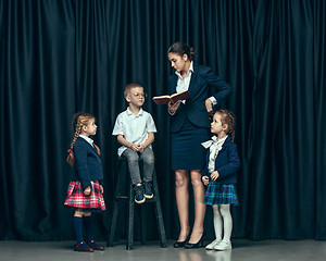 Image showing Cute stylish children on dark studio background. The beautiful teen girls and boy standing together