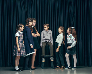 Image showing Cute stylish children on dark studio background. The beautiful teen girls and boy standing together