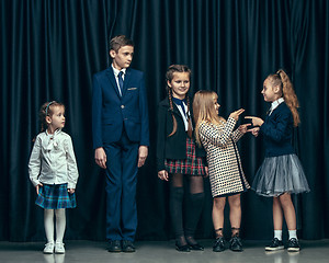 Image showing Cute stylish children on dark studio background. The beautiful teen girls and boy standing together