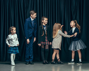 Image showing Cute stylish children on dark studio background. The beautiful teen girls and boy standing together