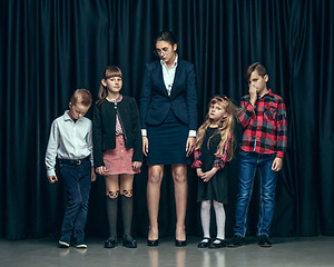 Image showing Cute stylish children on dark studio background. The beautiful teen girls and boy standing together