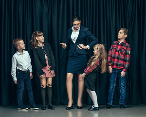 Image showing Cute stylish children on dark studio background. The beautiful teen girls and boy standing together