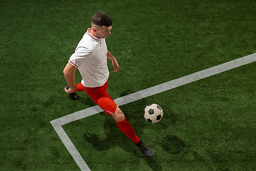 Image showing Football player tackling ball over green grass background