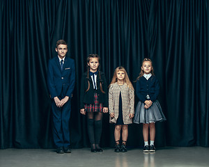 Image showing Cute stylish children on dark studio background. The beautiful teen girls and boy standing together