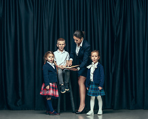 Image showing Cute stylish children on dark studio background. The beautiful teen girls and boy standing together