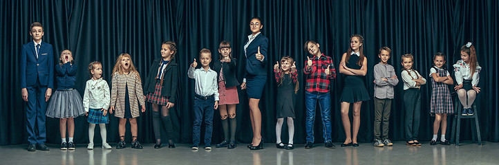 Image showing Cute stylish children on dark studio background. The beautiful teen girls and boy standing together