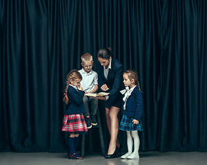 Image showing Cute stylish children on dark studio background. The beautiful teen girls and boy standing together