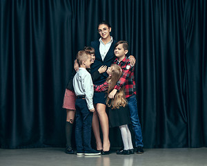 Image showing Cute stylish children on dark studio background. The beautiful teen girls and boy standing together