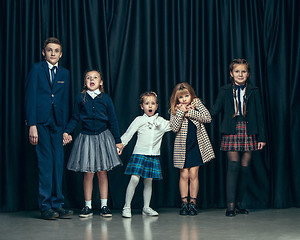 Image showing Cute stylish children on dark studio background. The beautiful teen girls and boy standing together