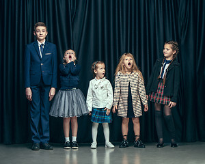 Image showing Cute stylish children on dark studio background. The beautiful teen girls and boy standing together