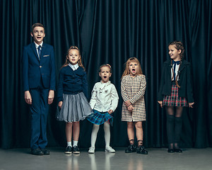 Image showing Cute stylish children on dark studio background. The beautiful teen girls and boy standing together