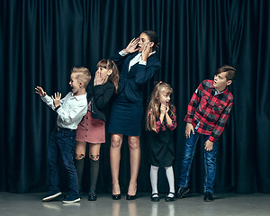 Image showing Cute stylish children on dark studio background. The beautiful teen girls and boy standing together