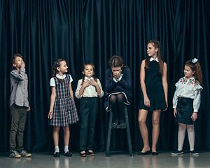 Image showing Cute stylish children on dark studio background. The beautiful teen girls and boy standing together