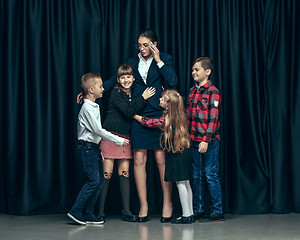 Image showing Cute stylish children on dark studio background. The beautiful teen girls and boy standing together