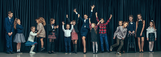 Image showing Cute stylish children on dark studio background. The beautiful teen girls and boy standing together