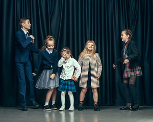 Image showing Cute stylish children on dark studio background. The beautiful teen girls and boy standing together