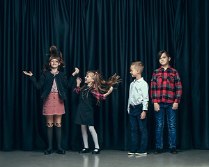 Image showing Cute stylish children on dark studio background. The beautiful teen girls and boy standing together