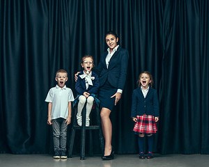 Image showing Cute stylish children on dark studio background. The beautiful teen girls and boy standing together