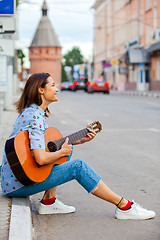 Image showing Girl in a blue shirt and jeans with a guitar in the old town