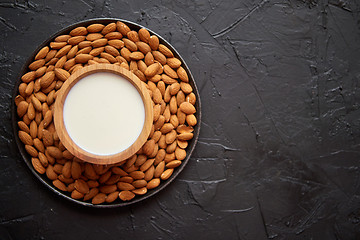 Image showing Composition of almonds seeds and milk, placed on black stone background.