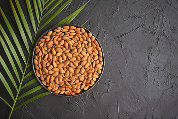 Image showing Composition of Whole almond nuts in black plate placed on black stone table