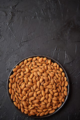 Image showing Whole almond nuts in black plate placed on black stone table