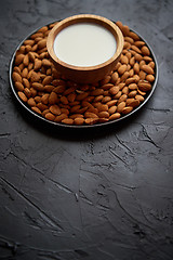 Image showing Composition of almonds seeds and milk, placed on black stone background.