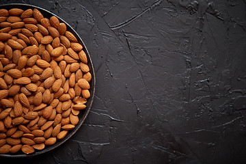 Image showing Whole almond nuts in black plate placed on black stone table