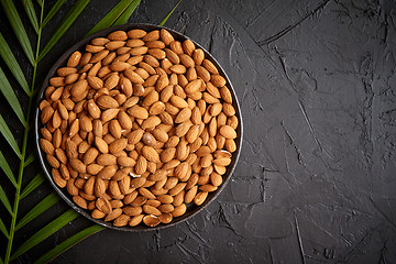 Image showing Composition of Whole almond nuts in black plate placed on black stone table