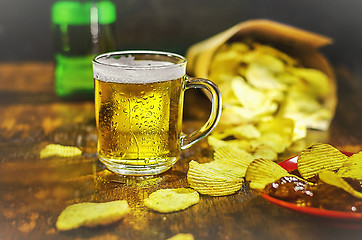 Image showing A glass of cold beer and chips on a wooden table. The concept of