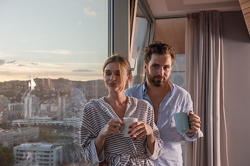 Image showing young couple enjoying evening coffee by the window