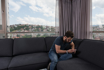 Image showing young casual man using a mobile phone at home