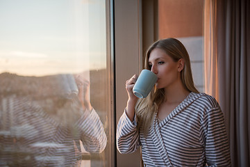 Image showing young woman enjoying evening coffee by the window