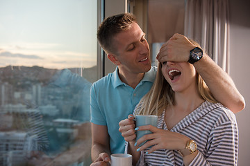 Image showing young couple enjoying evening coffee by the window