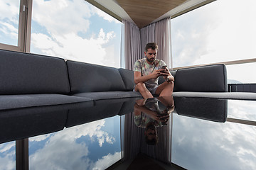 Image showing young casual man using a mobile phone at home