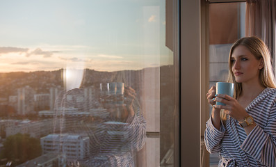 Image showing young woman enjoying evening coffee by the window