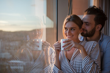 Image showing young couple enjoying evening coffee by the window